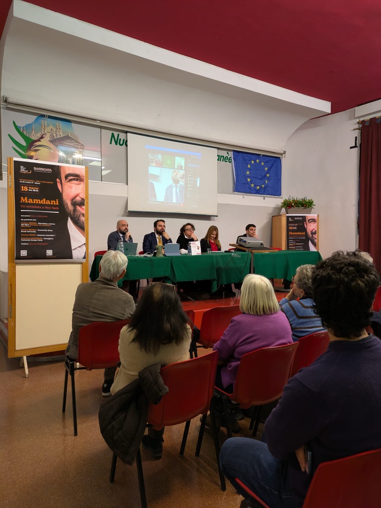 Vista della sala con i banner di Effetto Mamdani